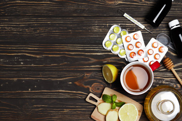 cup of hot tea with honey, ginger, lemon and mint on a wooden background