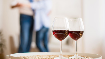 Loving couple dancing with glasses of red wine on foreground