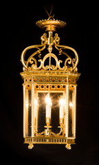 Antique decorative hanging brass hall lantern light illuminated glowing isolated on black