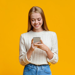 Beautiful Girl Messaging On Smartphone Over Orange Background