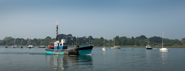 Old small English commercial fishing boat leaving to go to sea