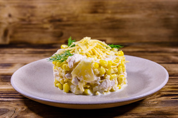 Festive salad with chicken breast, canned pineapple, cheese, sweet corn and mayonnaise on wooden table
