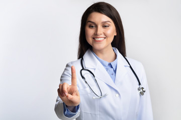 Fototapeta premium Doctor Woman Touching Invisible Touchscreen Standing Over Gray Background