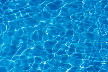 Fototapeta na wymiar Water ripples on blue tiled swimming pool background. Top view