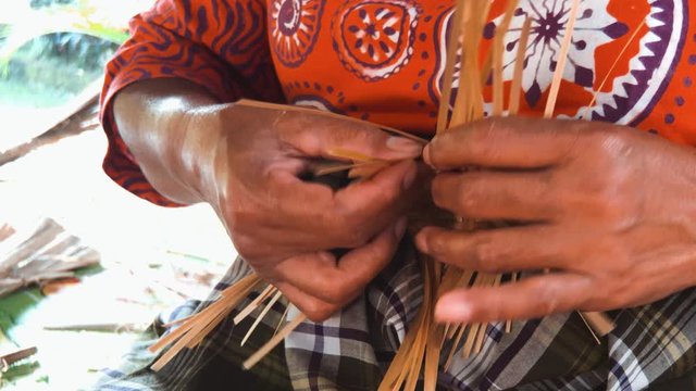 Close up shot of a woman's hand working on a traditional bamboo handwork