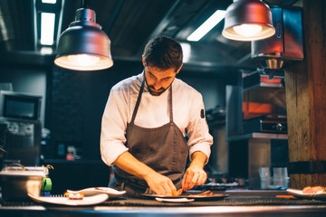 Chef serving food on plates in the kitchen of a restaurant