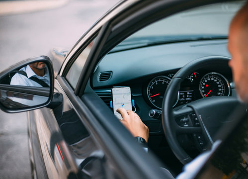 Businessman driving vehicle and using smartphone