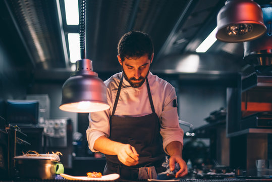 Chef serving food on plates in the kitchen of a restaurant