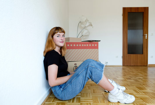 Smiling young student sitting on the floor during move