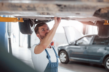 Attention needed. Employee in the blue colored uniform works in the automobile salon