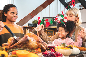 Thanksgiving Celebration Tradition Family Dinner Concept.family having holiday dinner and cutting turkey.Young black adult woman and her daughter happy..