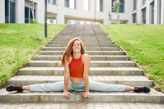 Young woman doing the splits on outdoor stairs