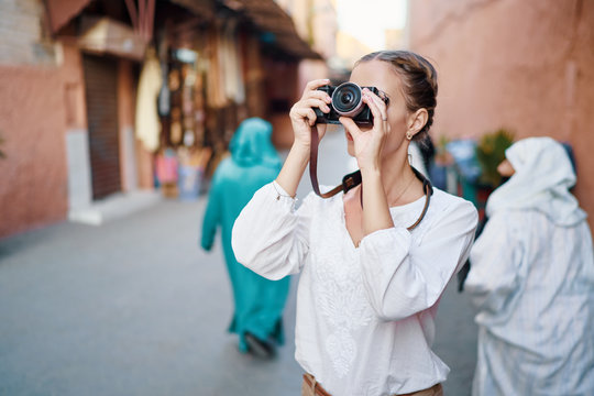 Tourism and technology. Happy young woman taking photo of  Marrakesh old town. Traveling by Morocco.