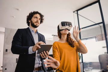 Businessman and businesswoman with VR glasses and tablet in office