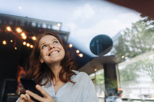 Happy redheaded woman with cell phone in a cafe
