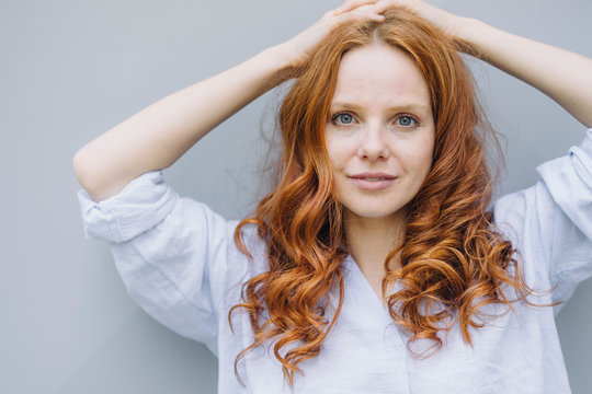 Portrait of beautiful redheaded woman at a wall