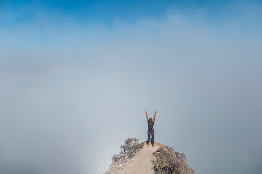 Woman with raised arms on view point, Ijen volcano, Java, Indonesia