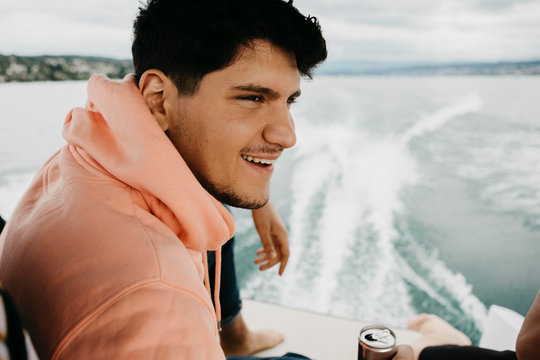 Happy young man having a drink on a boat trip on a lake