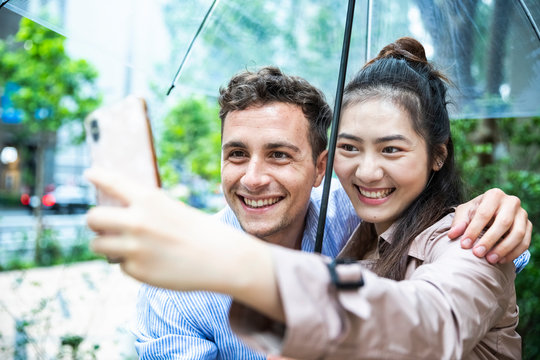 Happy couple with umbrella taking a selfie in Ginza, Tokyo, Japan