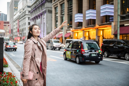Young woman hailing a taxi at a street in Ginza, Tokyo, Japan