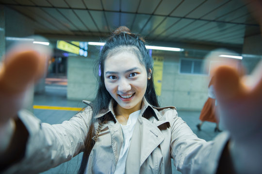 Selfie portrait of smiling young woman at Ginza underground station, Tokyo, Japan
