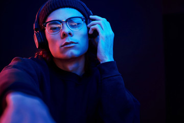 This is my favourite song. Studio shot in dark studio with neon light. Portrait of serious man