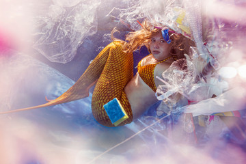 Teenage mermaid girl surrounded by plastic waste under water