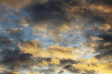 Obraz premium Golden fiery sunset in the blue sky. Crepuscular rays, streaming through gaps in clouds