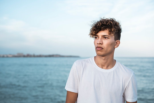 Portrait of young man with curly hair by the sea