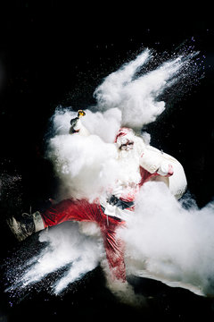 Santa Claus with exploding snow bomb against black background