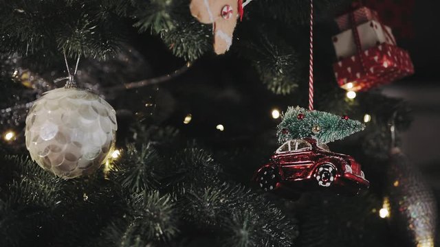 christmas decoration elements white ball covered with sequins and red car with pine on roof closeup slow motion