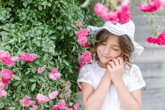 Portrait of smiling girl with closed eyes at rosebush