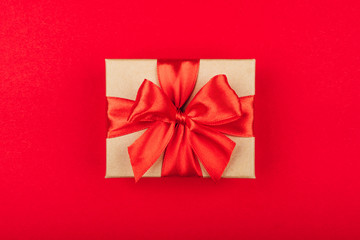 Cardboard gift box with bow on red background.