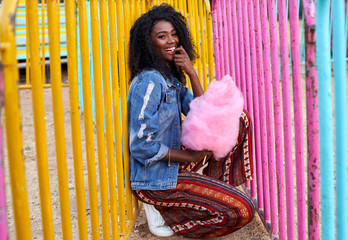 Portrait of happy young woman with pink candy floss at fair