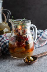 glass decanter with olives and pepper with cheese in olive oil