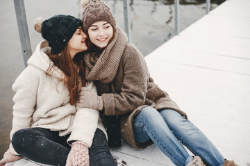 two bright and merry girls sitting in the frozen snowy park