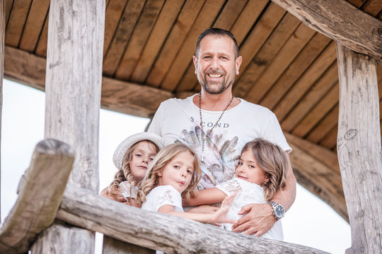 Happy father with three triplet sisters at a treehouse