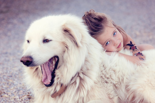 Portrait of little girl cuddling yawning white dog
