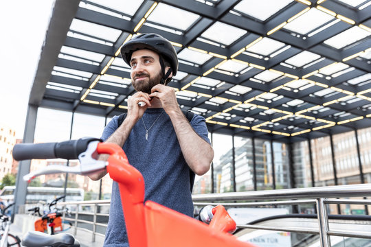 Man fastening safety helmet for rental scooter