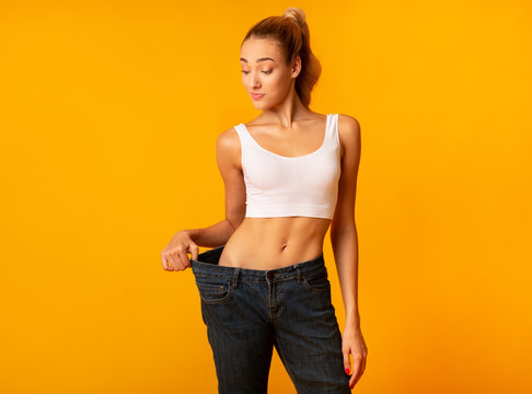 Slim Woman In Oversize Jeans Posing Standing In Studio