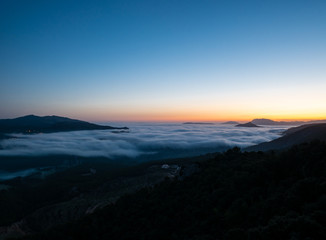 Plakat sunrise with low clouds and mountains silhouettes