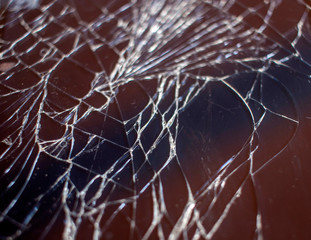Cracked smart phone screen close-up. Broken glass texture background with cracks.