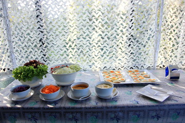 Prepares Salad and salad dressing, including fried eggs on the table.