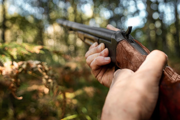 Finger on the trigger of a hunting rifle in the autumn forest close-up. The hunting period, the...