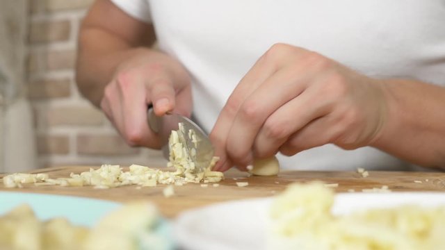 male hands cut garlic on a wooden board. close-up
