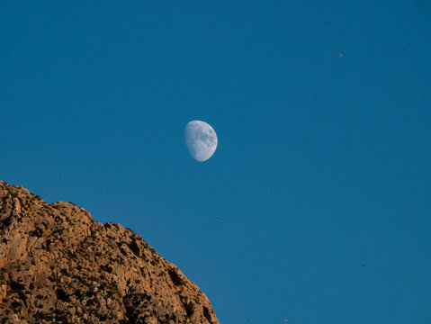 crescent moon with high contrast next to a mountain peak