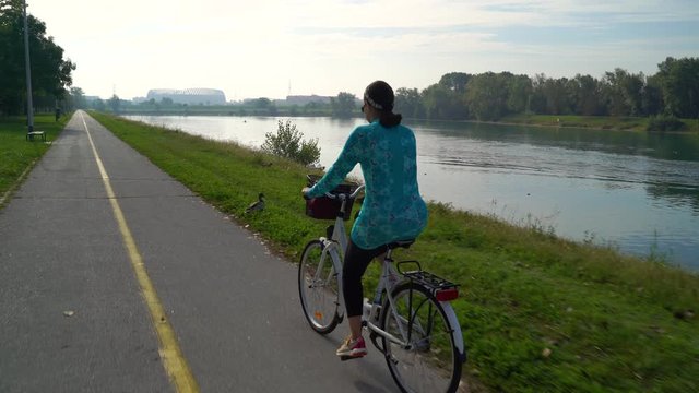 Middle age woman riding a bicycle during the morning at lake, Zagreb, Croatia.