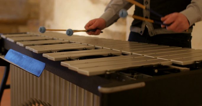 Man body playing the vibraphone in old french monastery. this metal xylophone, is like glockenspiel. here played in medieval french unesco abbey church
