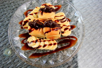 Toast with bananas topping with chocolate,That sweet on the table glass.