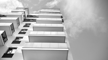  Fragment of a facade of a building with windows and balconies. Modern home with many flats. Black and white.